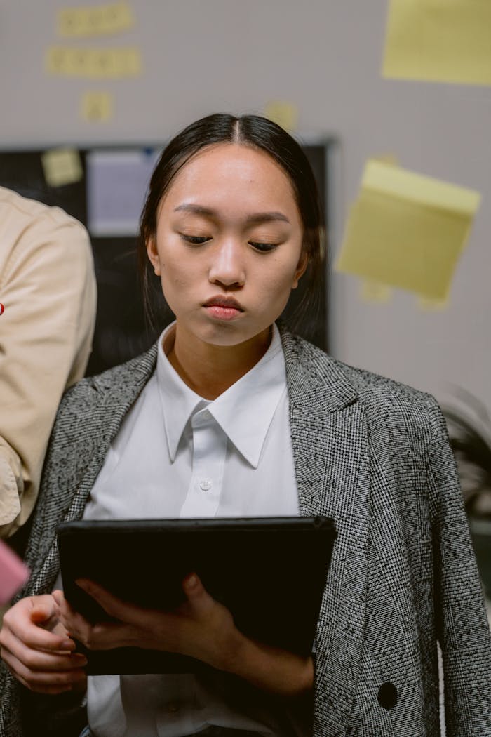 Focused woman using tablet in modern office, surrounded by sticky notes.